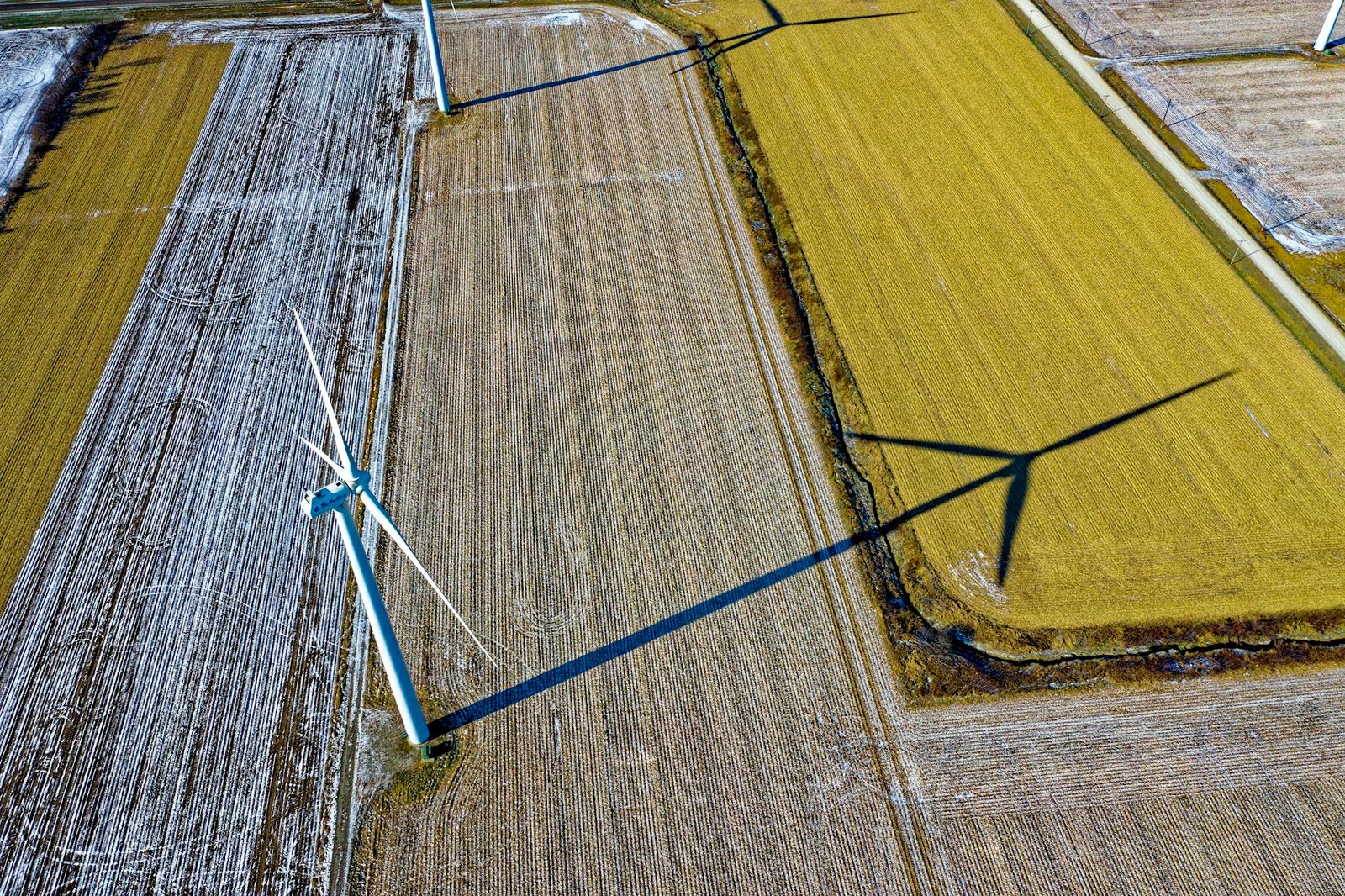 High-angle shot of wind turbines casting shadows on farmland in Dodge Center, MN.